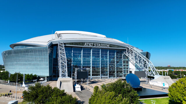 Aerial drone photo of AT&T Stadium in Arlington, Texas, on a clear sunny day. The image captures the stadium&rsquo;s modern architectural design with its iconic retractable roof