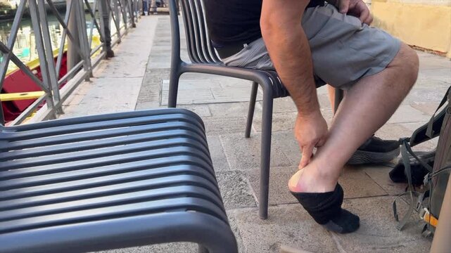 Tourist applying bandage to ankel after blister appears from walking - close up