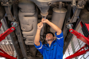 Mechanic repairing car driveshaft under vehicle lift