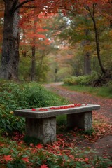 Naklejka premium Peaceful stone bench surrounded by vibrant autumn foliage in a serene forest park, featuring red and orange maple leaves scattered on the ground, perfect for nature background or seasonal landscape co
