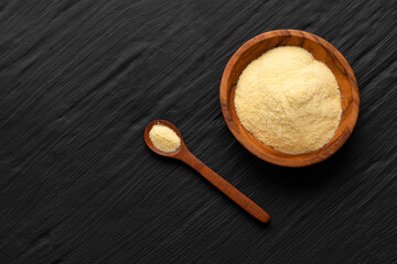Coarse wheat semolina flour in a bowl and wooden spoon - Triticum