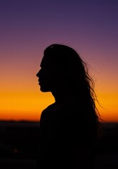 Silhouette of Woman with Wet Hair Standing at Sunset in Vibrant Sky