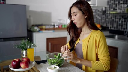 Asian adult woman eating fresh green salad healthy meal home kitchen promoting wellness vibrant living mindful nutrition daily routine lifestyle