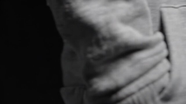 Close up of a grey hoodie drawstring against black background