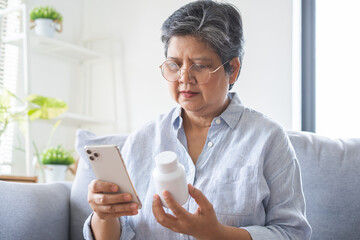 Health care concept, asian senior woman using smart phone reading, searching prescription on bottle...