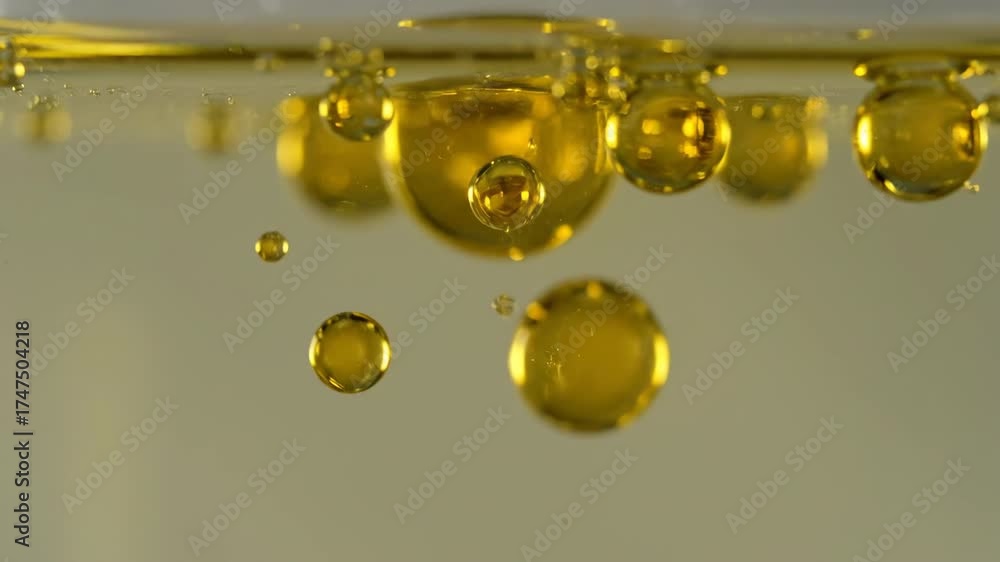 Wall mural macro slow motion of golden oil drops gently separating and reforming within a transparent liquid tr