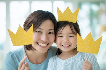 A joyful mother and daughter pose together, holding yellow crown cutouts, showcasing happiness and a playful moment.