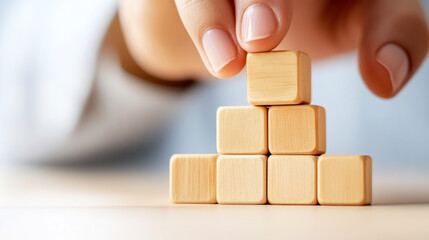 Building Block Harmony: A hand carefully places a wooden block atop a pyramid of other blocks, symbolizing concepts of building, construction, and potential.