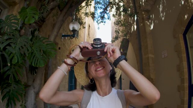 A girl walks around the city of Jaffa and photographs landmarks. A girl travels around Israel and shoots content for her blog. A tourist with a camera.