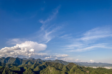 Vast Mountain Range Under Clear Blue Sky with Fluffy Clouds