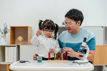 toddler girl scientist study using pipette dropping liquid with test tube and beaker. learning science with father