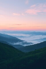 Obraz premium Majestic sunrise over rolling green hills covered in mist and fog, with layered mountain ranges fading into the horizon under a soft pastel sky, creating a peaceful natural landscape background for de