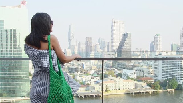 Bangkok, Thailand - 11th february, 2024: Attractive elegant woman tourist wear dress enjoy shopping mall look out famous viewpoint over river in southeast asia popular destination Bangkok city