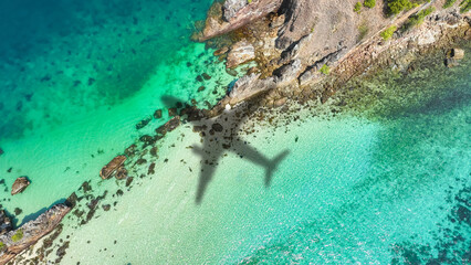 Aerial view of shadow passenger plane silhouette and sandy beach blue sea with waves at sea beach summer vacation sea travel concept	