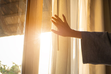 woman's hand She opened the curtains on the window. There was morning light through the window in her room, looking at the view of the mountains and trees as the sun rose   © Media 