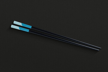 Chopsticks in dark material, placed on a black textured background