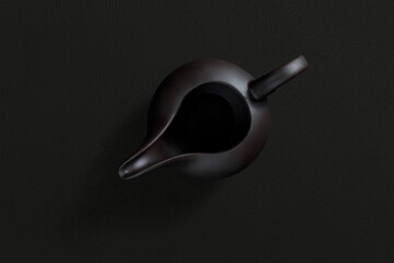 Ceramic teapot with lid and spout, top view on dark background
