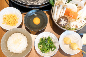 Hot pot ingredients displayed harmoniously on a wooden table with various side dishes. Top view