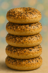 Stack of everything bagels with sesame and poppy seeds on pastel background