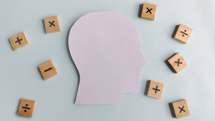 Human head silhouette surrounded by scattered wooden math symbols, representing complex calculations, educational challenges, and deep analytical thought.