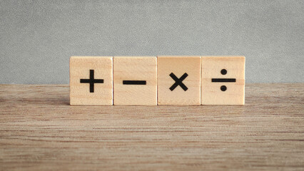 Four fundamental math operation signs on wooden blocks: addition, subtraction, multiplication, and division for education and business concepts.