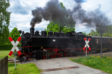 Schwarze Dampflok 99 758 mit G&uuml;ter- und Personenwagen an Bahn&uuml;bergang in Sachsen.
Traditionszug der Zittauer Schmalspurbahn &ndash; technisches Kulturerbe und Touristenmagnet zugleich