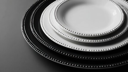Stack of elegant, beaded-edge plates, alternating white and dark, angled close-up view