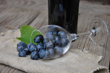 juicy grapes in an overturned glass glass on a wooden table with burlap. wine making concept