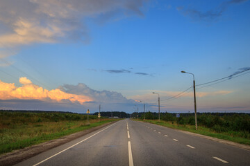 Long, empty road with a few trees in the background