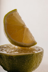 Macro of fresh lime slice on top of half lime, bright juicy texture and citrus freshness.