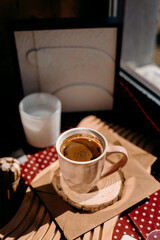 Cozy coffee scene with pink cup, candle and home decor on sunlit windowsill. Warm morning atmosphere.