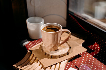 Bright morning light on pink coffee cup with candle and glasses on windowsill. Cozy home vibe.