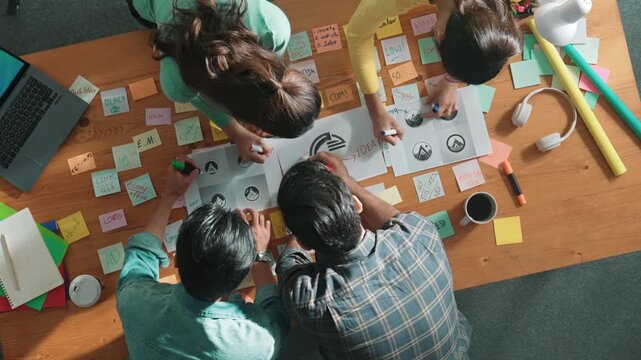 Time lapse of business team put graphic logo on meeting table with colorful sticky notes and start to design while explain idea. Project manager walking at group while explain concept art. Symposium.