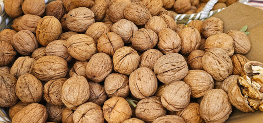 A close-up shot of whole unshelled walnuts in a rustic market setting in Spain, showcasing natural textures and autumn harvest. nuts display