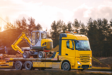 Industrial vehicle carrying excavator along highway