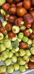 Close-up of fresh jujube fruits in different ripening stages, from green to reddish-brown, creating a natural texture and colorful contrast. Market produce