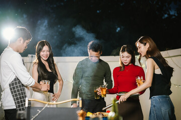 Group of friends having a fun backyard barbecue party at night, grilling food, chatting, and enjoying drinks together in a joyful atmosphere.