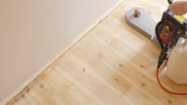 Floor sanding machine polishes wooden floor on home improvement project
