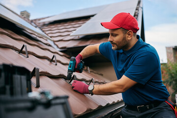 Roofer working on maintenance of roof of house. © Drazen