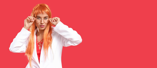Beautiful young woman in orange wig and eyeglasses on red background