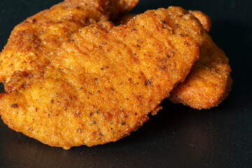 Spicy coated southern fried chicken pieces on a slate background backdrop.