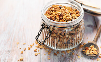 Granola breakfast cereal in glass jar with spoon