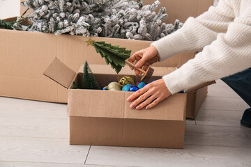 Woman putting Christmas toys in  cardboard box at home, closeup © Pixel-Shot