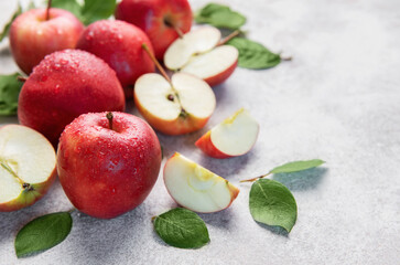 Fresh red apples with green leaves on grey background