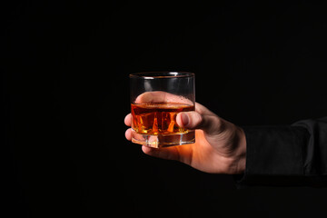 Male hand with glass of cold rum on black background