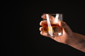 Male hand with glass of rum on black background