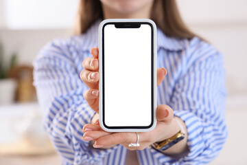 Young woman holding mobile phone with blank screen in kitchen, closeup