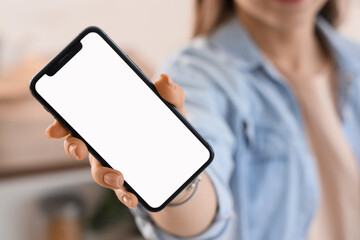 Young woman holding mobile phone with blank screen in kitchen, closeup