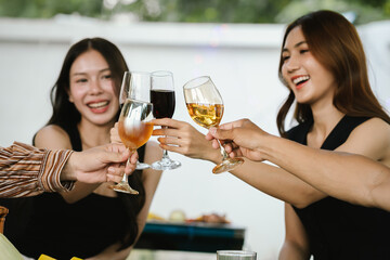 Friends clinking glasses of red and white wine in a cheerful toast, smiling and celebrating together in a joyful outdoor gathering.