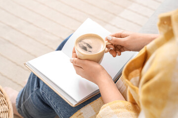 Obraz premium Woman relaxing with coffee and blank book, cozy leisure time at home, personal journaling and reading moment